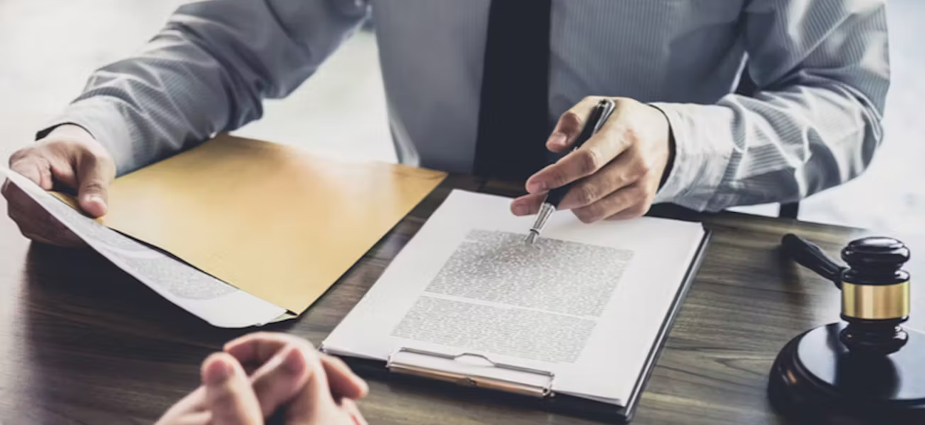 Une homme en costume montre avec son stylo-plume à son client les éléments relatifs à un contrat.