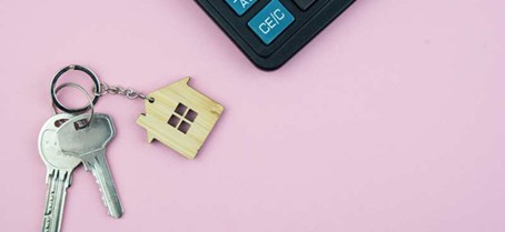 Des clés et une calculettes posés sur un fond rose